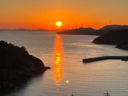 a sunset over a body of water with the sun setting at MY LODGE Naoshima in Naoshima