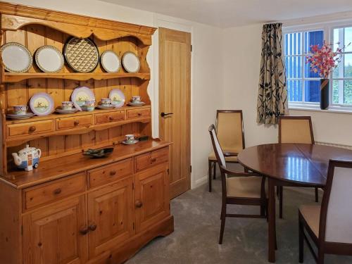 un comedor con un armario de madera con placas. en Windmill Cottage, en Little Eaton