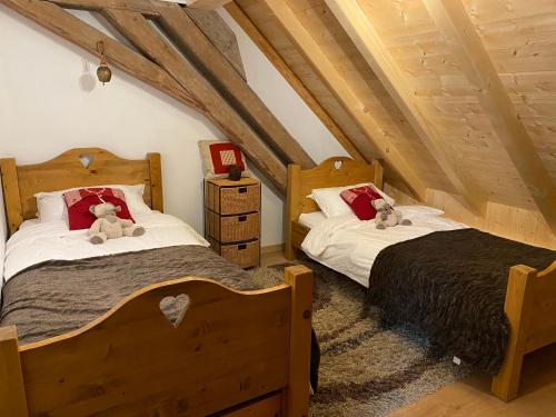 two beds with teddy bears on them in a attic at Le Bel appartement de Montagne in Bellevaux
