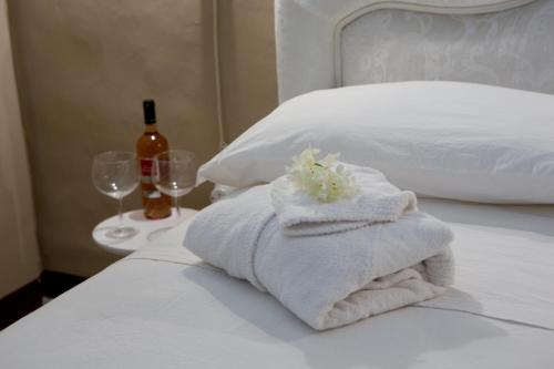 a pile of towels sitting on a bed with wine glasses at Dama Bianca Boutique Hotel Ostuni in Ostuni