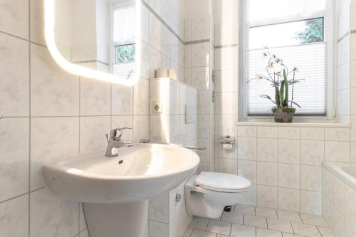 a white bathroom with a sink and a toilet at Villa Elbblick mit Garten in Tangermünde