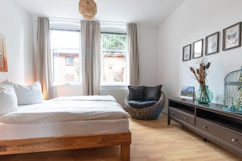 a bedroom with a bed and a chair and a window at Villa Elbblick mit Garten in Tangermünde