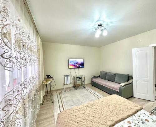 ein Wohnzimmer mit einem Bett und einer Couch in der Unterkunft 1 комнатная драмтеатр 1bedroom apartment in Öskemen