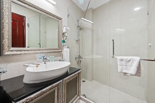 a white bathroom with a sink and a mirror at Chairmen Hotel in Doha