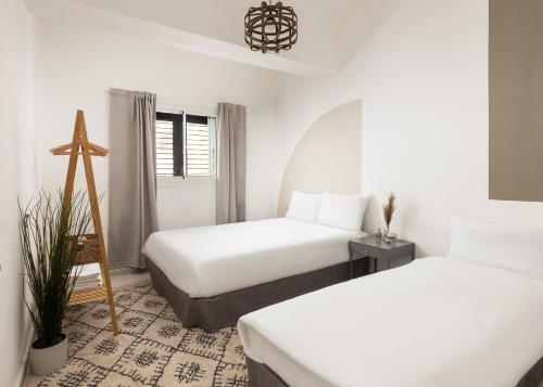 2 camas en una habitación con paredes blancas en Central By The Beach Apt, en Tel Aviv