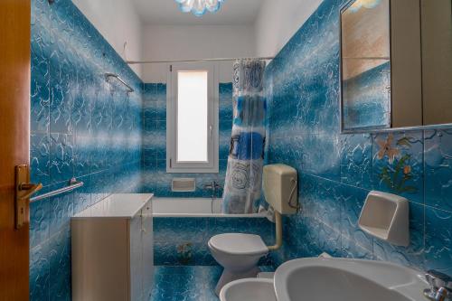 een blauw betegelde badkamer met een toilet en een wastafel bij Villa Salvo in Pachino