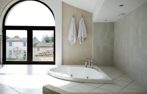 a bathroom with a large tub with a window at Château de La Vallade in Saint-Porchaire