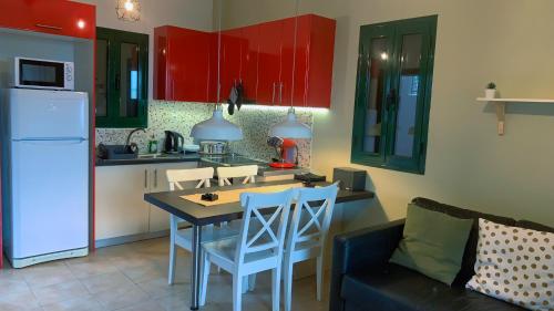 a kitchen with red cabinets and a table and chairs at Katarina Apartments Kefalonia - Sea View in Kefallonia