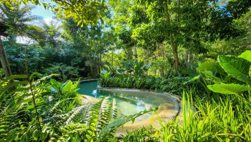 a swimming pool in the middle of a garden at Hotel Labaris Khao Yai in Mu Si