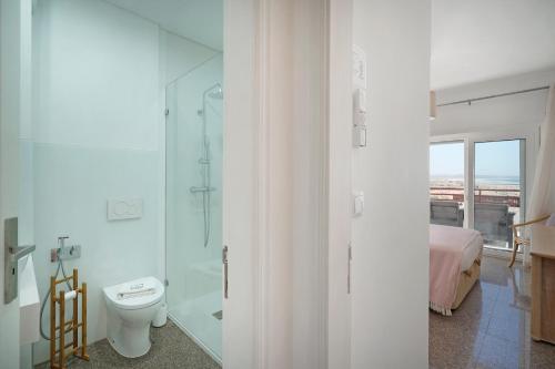 a bathroom with a toilet and a glass shower at Costa Beach Apartment by The Portuguese Butler in Costa da Caparica