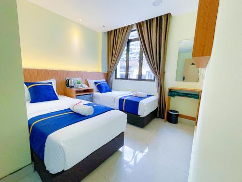 een hotelkamer met 2 bedden en een spiegel bij Astar Hotel Bukit Bintang in Kuala Lumpur