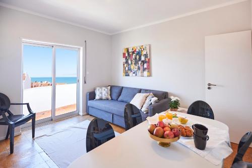 エリセイラにあるEriceira Center Sea View Apartment Iのフルーツのボウルが置かれたテーブルのあるリビングルーム