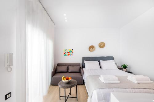 a white bedroom with two beds and a couch at Sunwaves Beach studio I in Ialysos