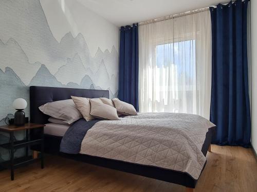 een slaapkamer met een bed met blauwe gordijnen en een raam bij Komfortowy Apartament Pod Lasem Villa Fonte 21 Polanica Zdrój in Polanica-Zdrój