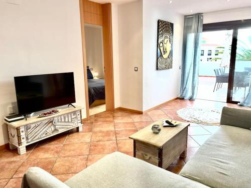 een woonkamer met een bank en een flatscreen-tv bij Apartamento Dhanvantari en Adeje Paradise in Playa Paraiso