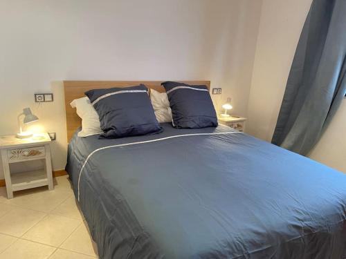 een bed met blauwe lakens en kussens in een slaapkamer bij Apartamento Dhanvantari en Adeje Paradise in Playa Paraiso