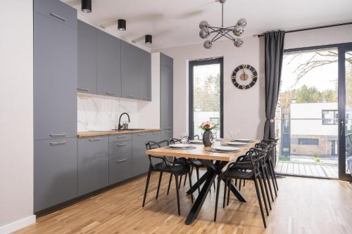 a kitchen and dining room with a wooden table and chairs at Apartamenty Olimpijska by RENT4YOU in Olsztyn