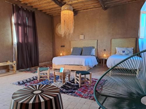 a bedroom with two beds and a chandelier at Riad Dar Tiziri in Zagora
