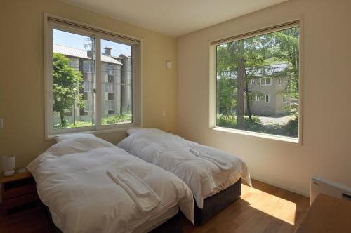 2 Betten in einem Schlafzimmer mit 2 Fenstern in der Unterkunft Cat's Villa Hakuba 4- Vacation STAY 82229 in Hakuba