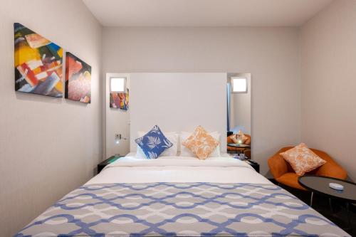 a bedroom with a large bed and a chair at Ramada Encore Doha by Wyndham in Doha