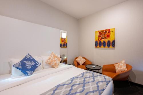 a bedroom with a large bed and a chair at Ramada Encore Doha by Wyndham in Doha