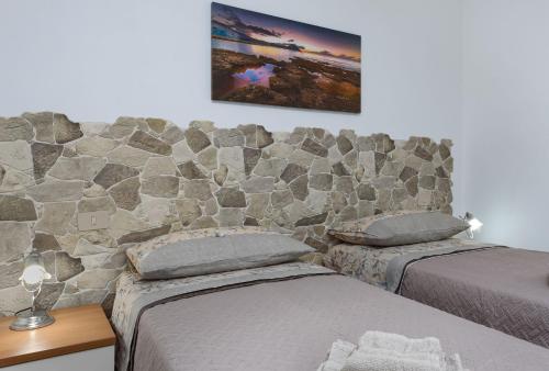 sypialnia z 2 łóżkami i kamienną ścianą w obiekcie Bedda Luna Villa w mieście San Vito lo Capo