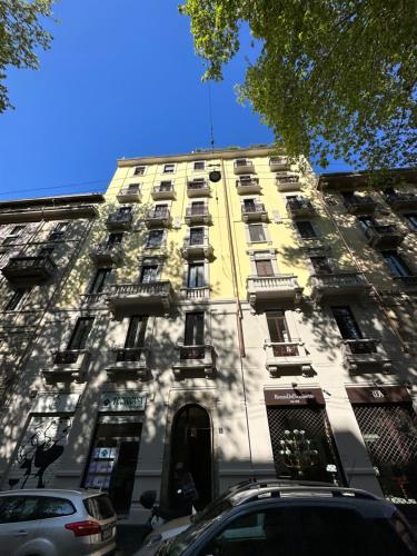 un grand bâtiment jaune avec des voitures garées devant lui dans l'établissement 4Rooms Milano, à Milan