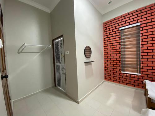 um quarto com uma parede de tijolos vermelhos e uma porta em Sasuka Guesthouse (Muslim Sahaja) em Marang