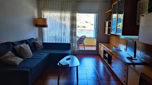 a living room with a blue couch and a table at Feliz Costa Brava Apartamento in Portbou