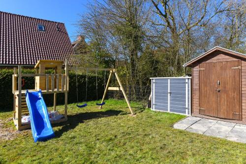 une cour avec une balançoire et un hangar dans l'établissement Ferienhaus Doppens Kanani, à Bensersiel