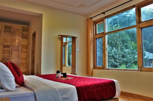 sypialnia z łóżkiem i dużym oknem w obiekcie Nirvana -A Balcony Rooms Hotel-A True View Of Mountains w mieście Manāli
