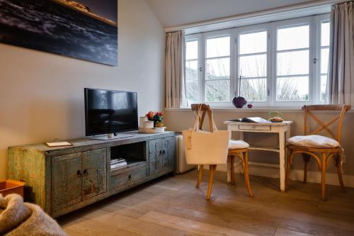 a living room with a television and a table and chairs at Kontorhaus Keitum in Keitum