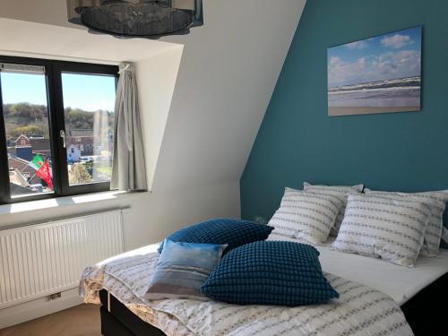 a bedroom with a bed with pillows and a window at Heerlijke vakantiehuizen in Egmond in Egmond aan Zee