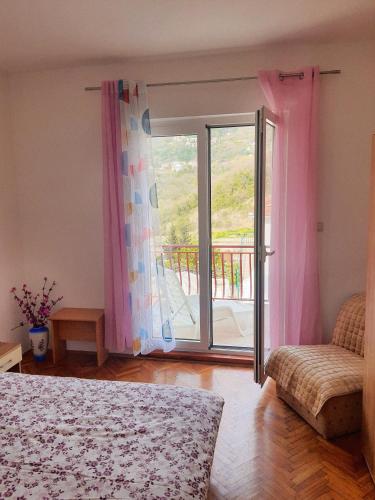 - une chambre avec un lit et une porte coulissante en verre dans l'établissement Apartman Krivokapic, à Igalo