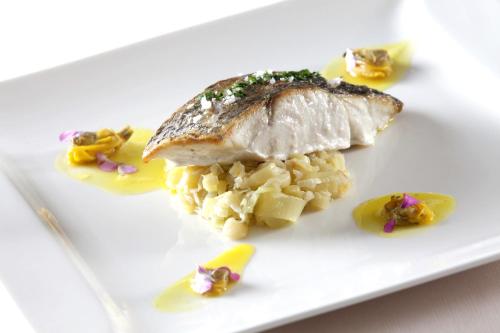 a white plate with a piece of fish and vegetables at Baia D'Argento in Porto Santo Stefano