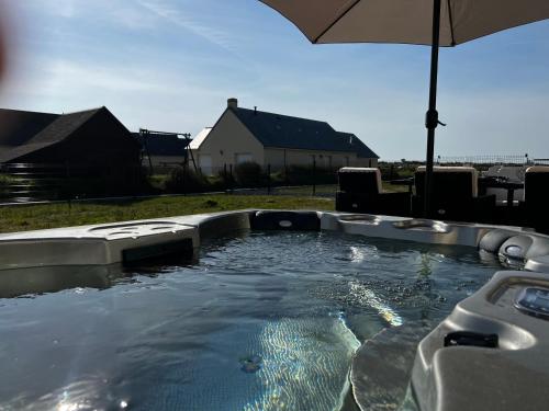 una vasca immersione ad acqua fredda con ombrellone in un cortile di Villa en bord de mer SPA / Sauna (N) a Bretteville-sur-Ay