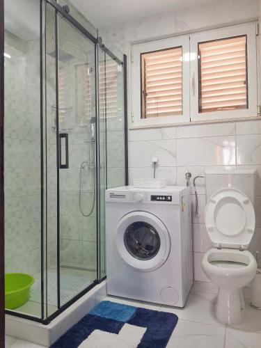 a bathroom with a washing machine and a toilet at Apartman Krivokapic in Igalo