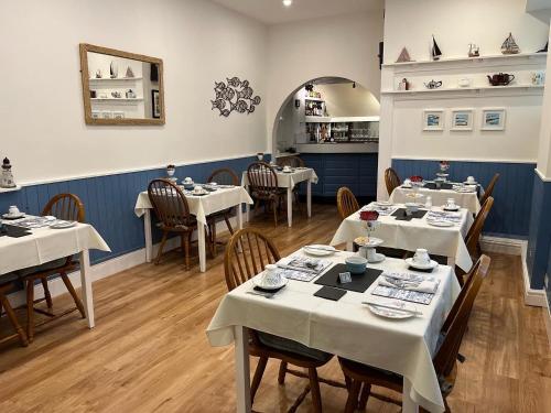 uma sala de jantar com mesas e cadeiras com toalhas de mesa brancas em Awel Mor em Criccieth