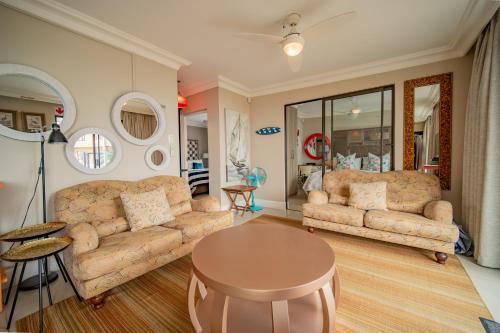 a living room with two couches and a table at On the Beach Guesthouse Jeffreys Bay in Jeffreys Bay