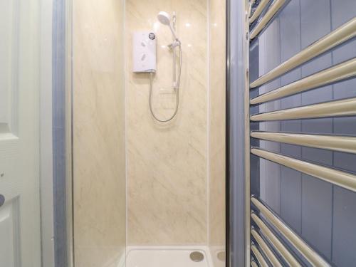 a shower in a bathroom with blue tiles at Cheriton in Tuxford