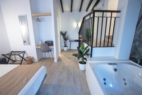 a white bathroom with a tub and a bedroom at Vitium C&oacute;rdoba in C&oacute;rdoba