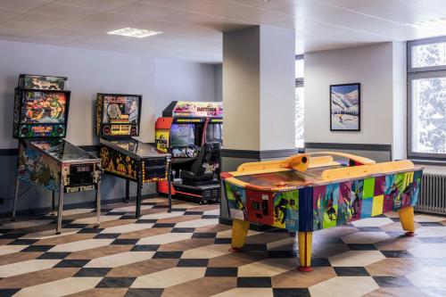 a room with three arcade games and a checkerboard floor at Hotel Altein Arosa, a Faern Collection Resort in Arosa