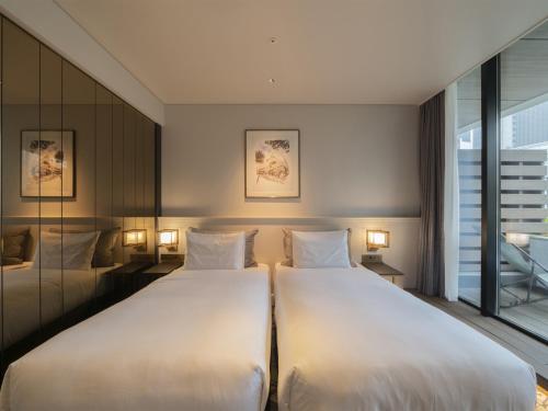 two beds in a hotel room with a window at GINZA HOTEL by GRANBELL in Tokyo