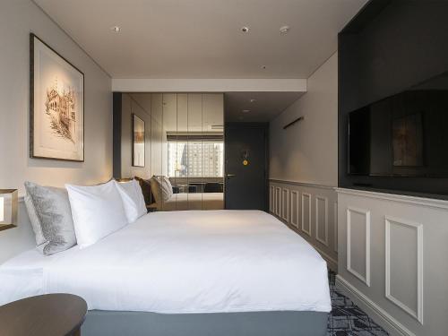 a bedroom with a large bed and a flat screen tv at GINZA HOTEL by GRANBELL in Tokyo