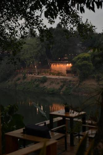 a picnic table next to a river at night at Moonlight Champa Riverview in Luang Prabang