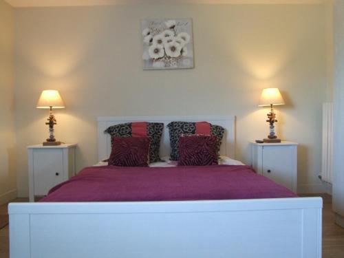a bedroom with a white bed with purple sheets and two lamps at La Villa Port Winston - Face Mer B&B in Saint-Côme-de-Fresné