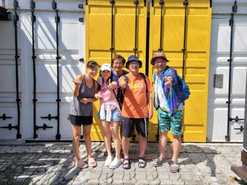 a group of people standing in front of a yellow garage at 20ft Sea Attic in Green Island