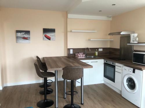 a kitchen with a wooden table and chairs in it at La Villa Port Winston - Face Mer B&B in Saint-Côme-de-Fresné
