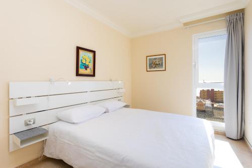 Un dormitorio blanco con una cama grande y una ventana. en Home2Book Stunning Sea Views El Porís, en Porís de Abona