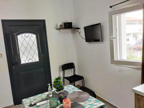 a room with a table and a door and a television at Nikolas' house in Nea Iraklia